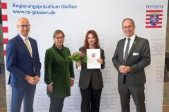 Foto: RP Gießen | Ministerialdirigent Andreas Monz (links), Regierungspräsident Dr. Christoph Ullrich (rechts) und Schulleiterin Beatrix Bunse (2. v. l.) gratulierten Kardelen Kadir (3. v. l.).