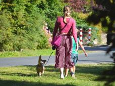 Frau geht mit Hund spazieren von hinten