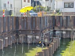 Tauchergruppe: Taucher mit Trockentauchanzug, Signalmann mit Sprechverbindung zum Taucher, Rettungstaucher (außerhalb des Bildes)