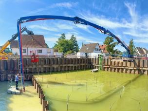 Herstellung der Unterwasserbetonsohle in der Baugrube des Pumpwerkes, Kontrolle der Einbauhöhe per Rotationslaser vom Arbeitsponton aus, Transport der Taucher per Mannkorb